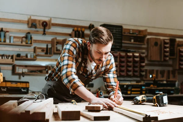 Selective focus of woodworker measuring wooden plank — Stock Photo