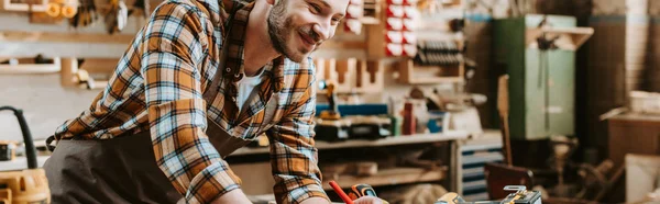 Panoramic shot of happy woodworker in workshop — Stock Photo