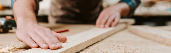 Panoramic shot of carpenter touching wooden plank — Stock Photo