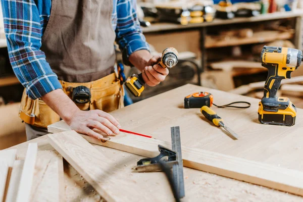 Cropped view of carpenter holding hammer drill — Stock Photo