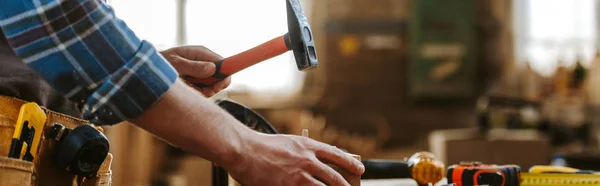 Panoramic shot of carpenter holding hammer in workshop — Stock Photo