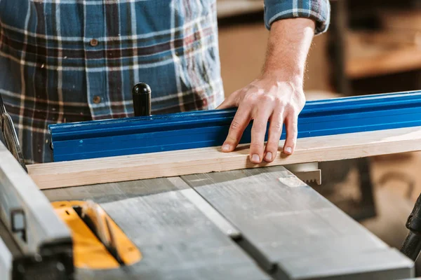 Cropped view of woodworker holding plank near circular saw — Stock Photo