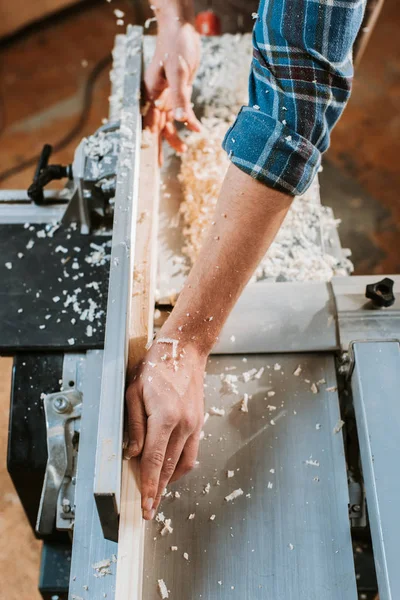 Ausgeschnittener Blick auf Handwerker, der Bretter in der Nähe von Kreissäge in Schreinerei hält — Stockfoto