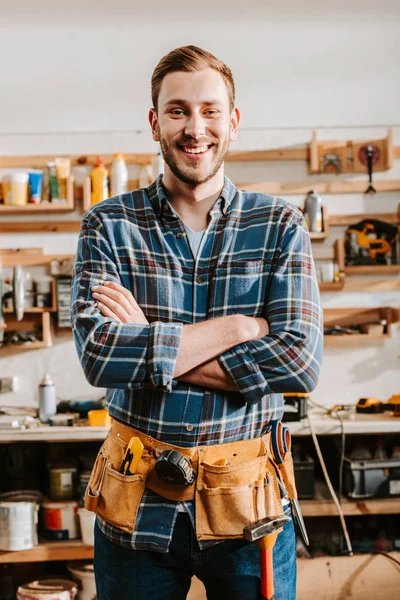Happy carpenter in apron standing with crossed arms — Stock Photo