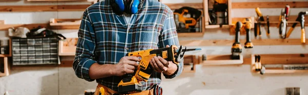 Panoramic shot of carpenter holding hammer drill — Stock Photo