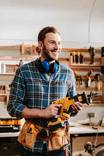 Fröhlicher bärtiger Tischler mit Hammerbohrmaschine — Stockfoto