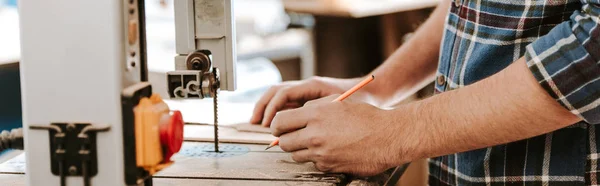 Panoramic shot of carpenter holding pencil in workshop — Stock Photo