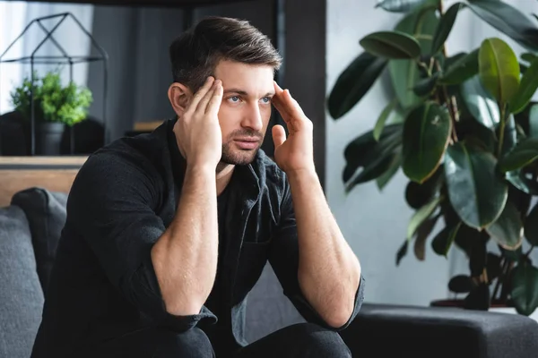 Hombre guapo en camisa con dolor de cabeza tocando la cabeza en el apartamento - foto de stock