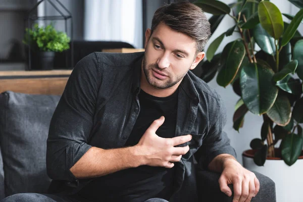 Handsome man in shirt having heart attack in apartment — Stock Photo