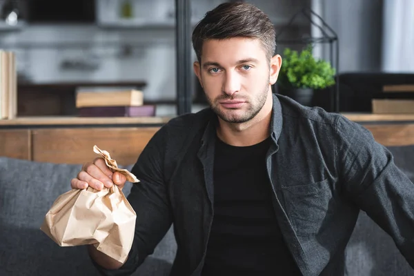 Handsome man with panic attack holding paper bag in apartment — Stock Photo