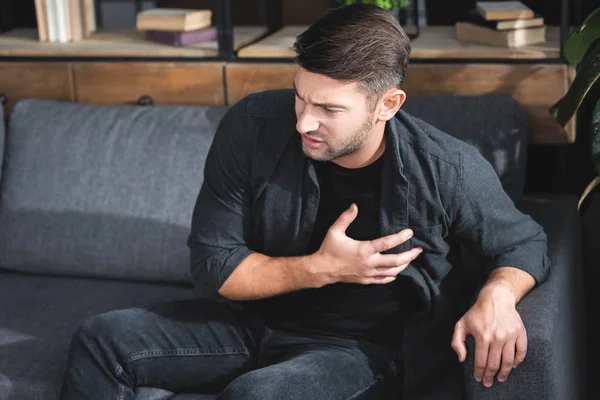 Hombre guapo en camisa teniendo un ataque al corazón en apartamento - foto de stock