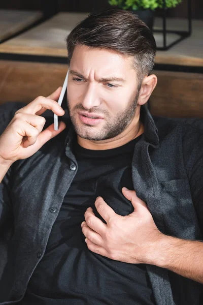 Schöner Mann mit Herzinfarkt und Smartphone in Wohnung — Stockfoto