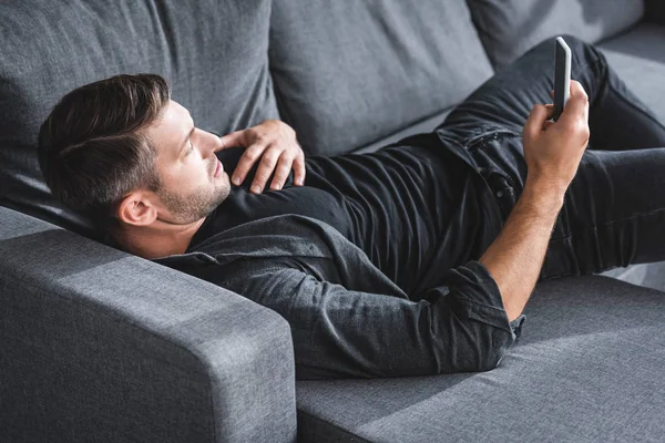 Visão de alto ângulo de homem bonito tendo ataque cardíaco e usando smartphone no apartamento — Fotografia de Stock