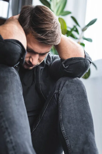 Selective focus of handsome man with headache touching head in apartment — Stock Photo