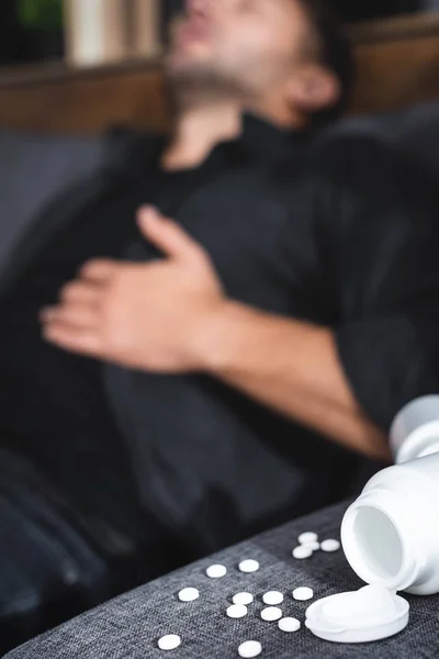 Selective focus of bottles and pills on grey sofa — Stock Photo