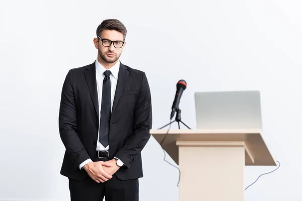 Selective focus of scared businessman in suit standing near podium tribune during conference isolated on white — Stock Photo