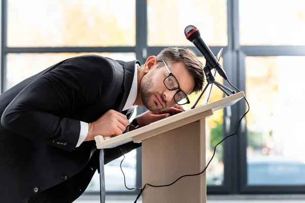 Scared businessman in suit standing at podium tribune during conference — Stock Photo