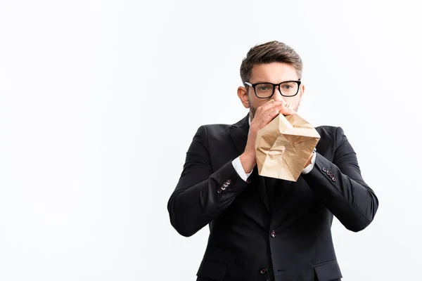 Испуганный бизнесмен в костюме дышит в бумажный пакет во время конференции изолированы на белом — стоковое фото