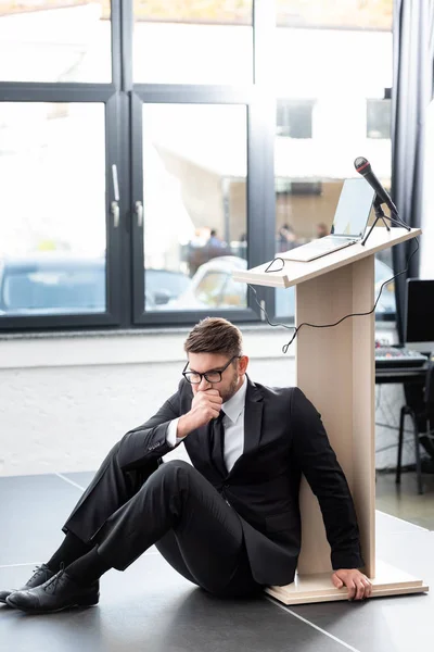 Scared businessman in suit sitting on floor during conference — Stock Photo