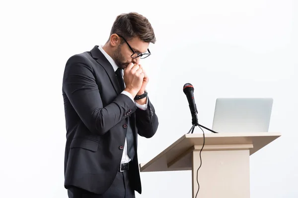 Испуганный бизнесмен в костюме, стоящий на трибуне во время конференции изолированный на белом — стоковое фото