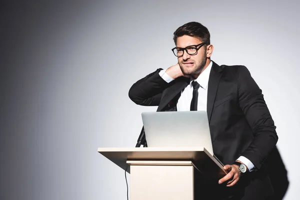 Scared businessman in suit standing at podium tribune and looking away during conference on white background — Stock Photo