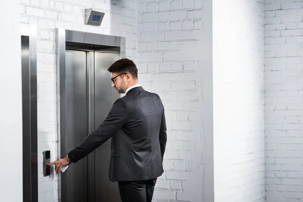 Homem de negócios de terno apertando botão de elevador no escritório — Fotografia de Stock