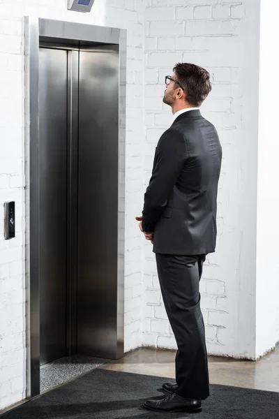 Hombre de negocios en ropa formal esperando ascensor en la oficina - foto de stock