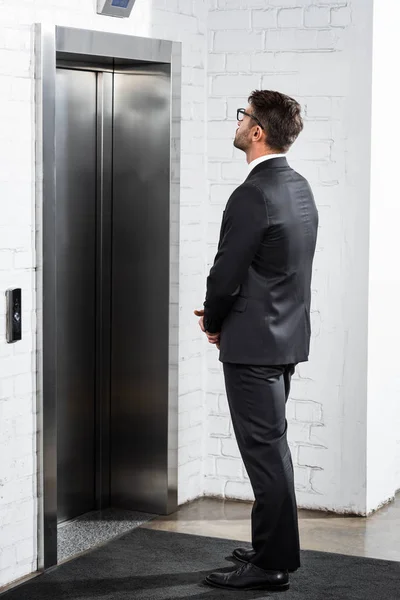 Hombre de negocios en ropa formal esperando ascensor en la oficina — Stock Photo