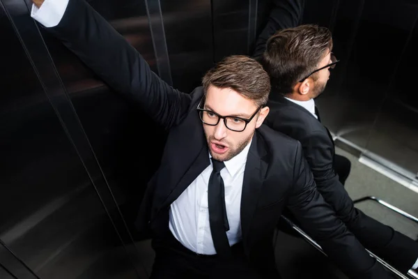 High angle view of scared businessman in suit with claustrophobia in elevator — Stock Photo