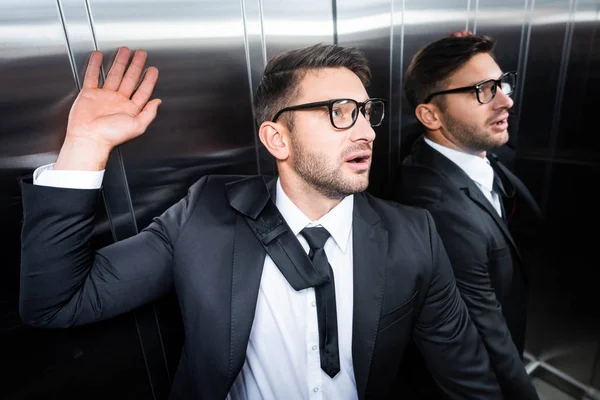 Hombre de negocios guapo y asustado en traje con claustrofobia en ascensor - foto de stock