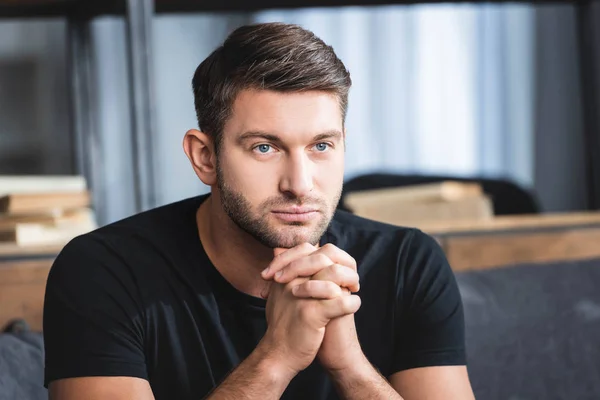 Handsome and pensive man with clenched hands looking away in apartment — Stock Photo