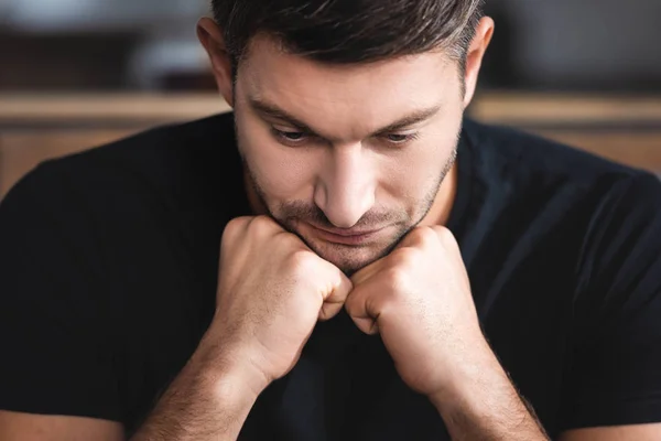 Handsome and sad man in t-shirt looking down in apartment — Stock Photo