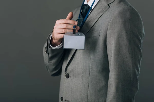 Vista recortada del hombre de traje con insignia aislada en gris - foto de stock