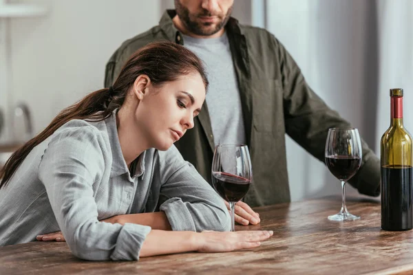 Разочарованная женщина держит бокал вина рядом с мужем — стоковое фото