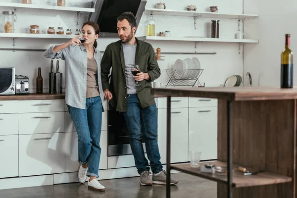 Selective focus of alcohol dependent couple drinking red wine on kitchen — Stock Photo