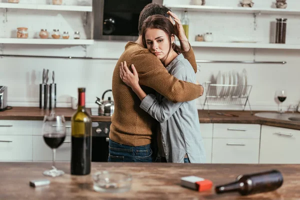 Foco seletivo do homem que apoia a esposa com o vício em álcool na cozinha — Fotografia de Stock