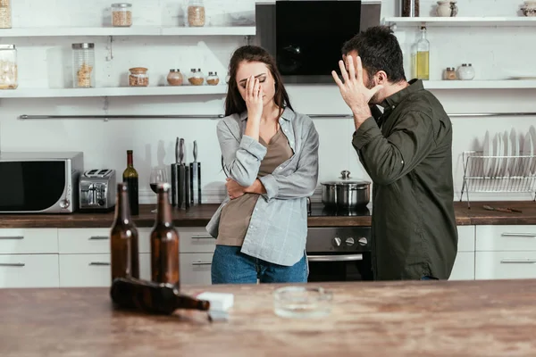 Focus selettivo dell'uomo arrabbiato che litiga con la moglie alcolizzata in cucina — Foto stock