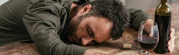 Homme ivre dormant sur la table avec du vin, vue panoramique — Photo de stock