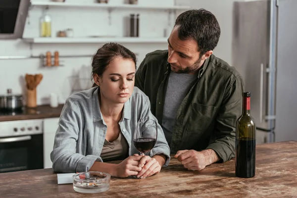 Hombre mirando a la mujer sosteniendo copa de vino en la cocina - foto de stock