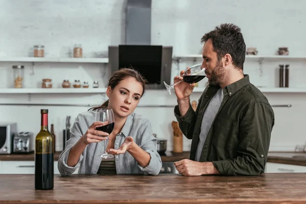 Alcohol addicted couple drinking wine and talking on kitchen — Stock Photo