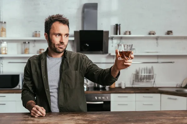 Uomo con bicchiere di whisky brindare a qualcuno in cucina — Foto stock