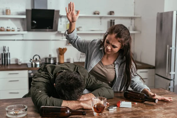 Mulher irritada brigando com marido bêbado na cozinha — Fotografia de Stock