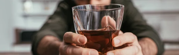 Selective focus of man holding whiskey glass in hands, panoramic shot — Stock Photo