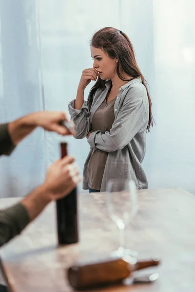 Enfoque selectivo de la mujer preocupada y el hombre abriendo la botella de vino en casa - foto de stock