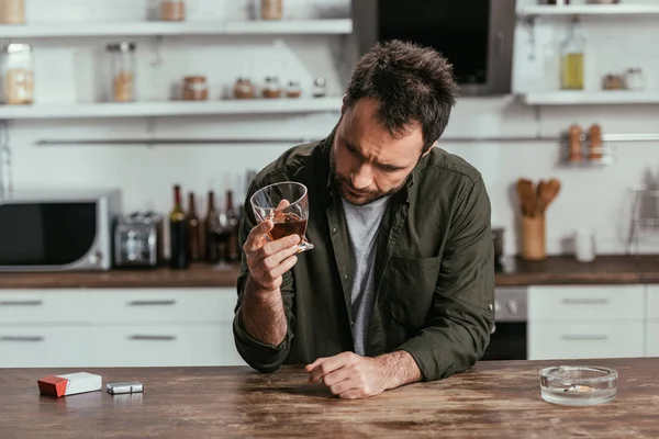 Besorgter alkoholabhängiger Mann hielt Whiskey-Glas in Küche — Stockfoto