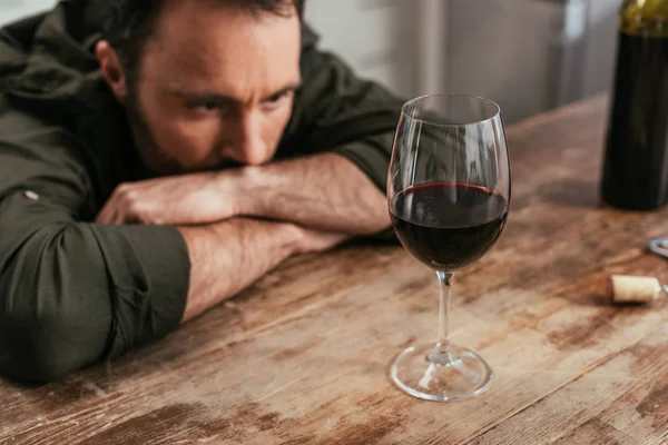 Selektiver Blick des nachdenklichen Mannes auf das Weinglas auf dem Tisch — Stockfoto