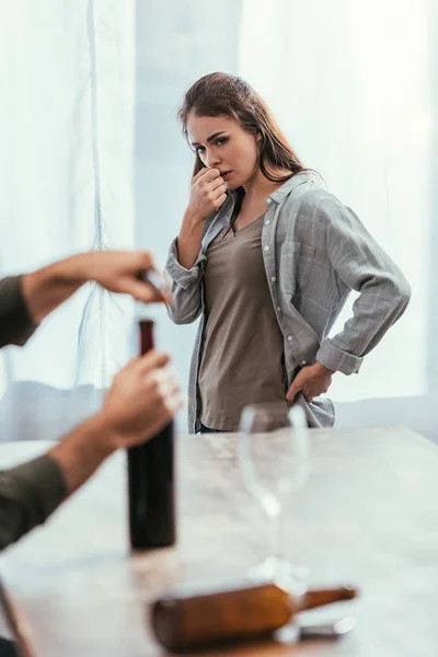 Foco seletivo da mulher preocupada olhando para o homem abrindo garrafa de vinho — Fotografia de Stock