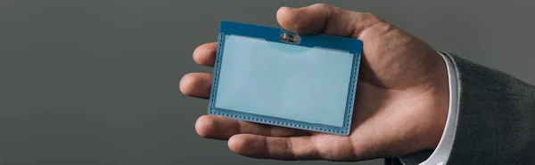 Cropped view of man holding badge isolated on grey, panoramic shot — Stock Photo