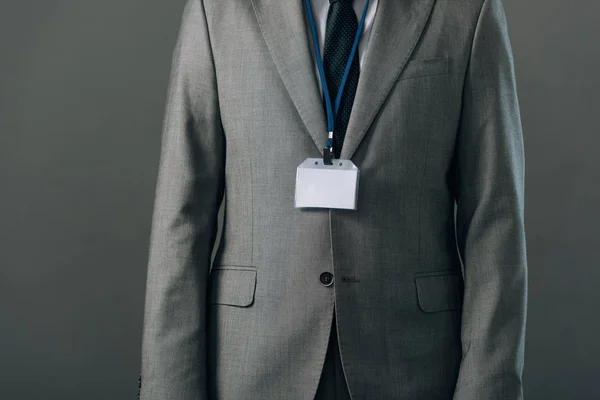 Vue recadrée de l'homme en costume avec insigne isolé sur gris — Photo de stock