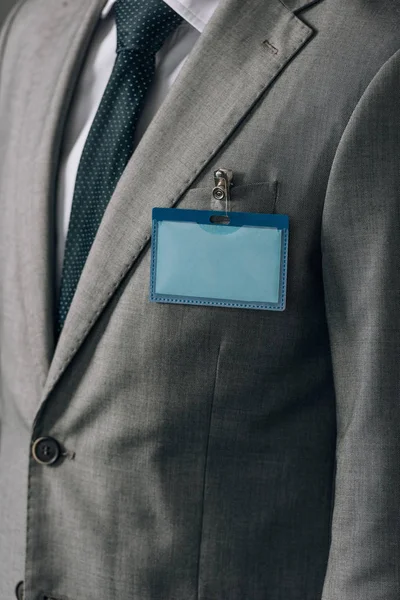 Cropped view of man with badge on grey suit — Stock Photo